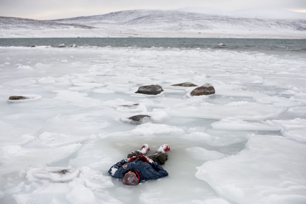 Person lying in ice in Arctic landscape