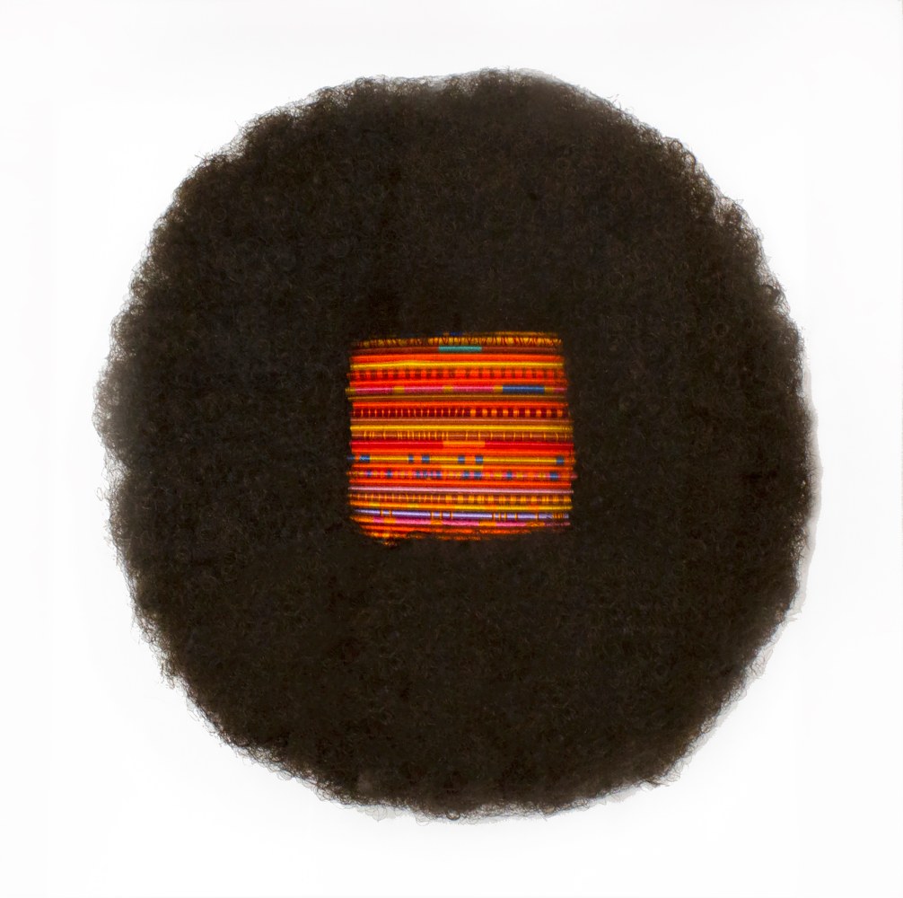 an afro wig with a block of combs in the center that have been woven through with colorful thread