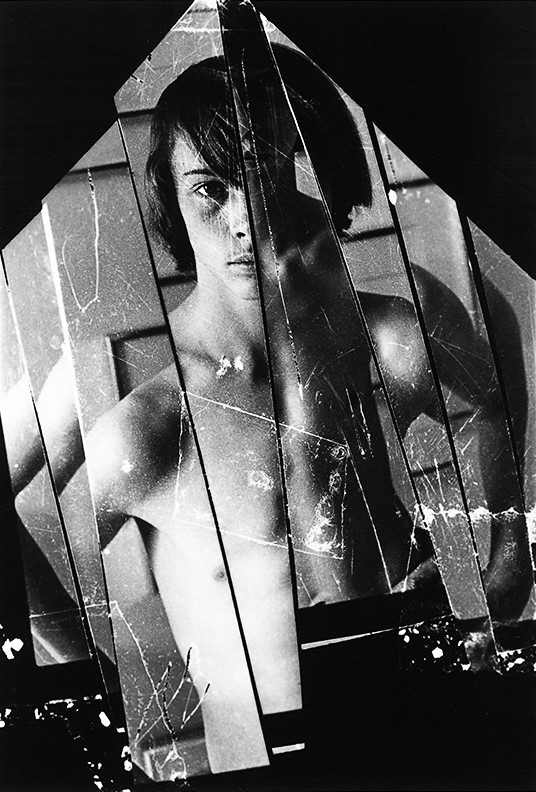 Black and white collage portrait of young man with bare chest and arms at waist.