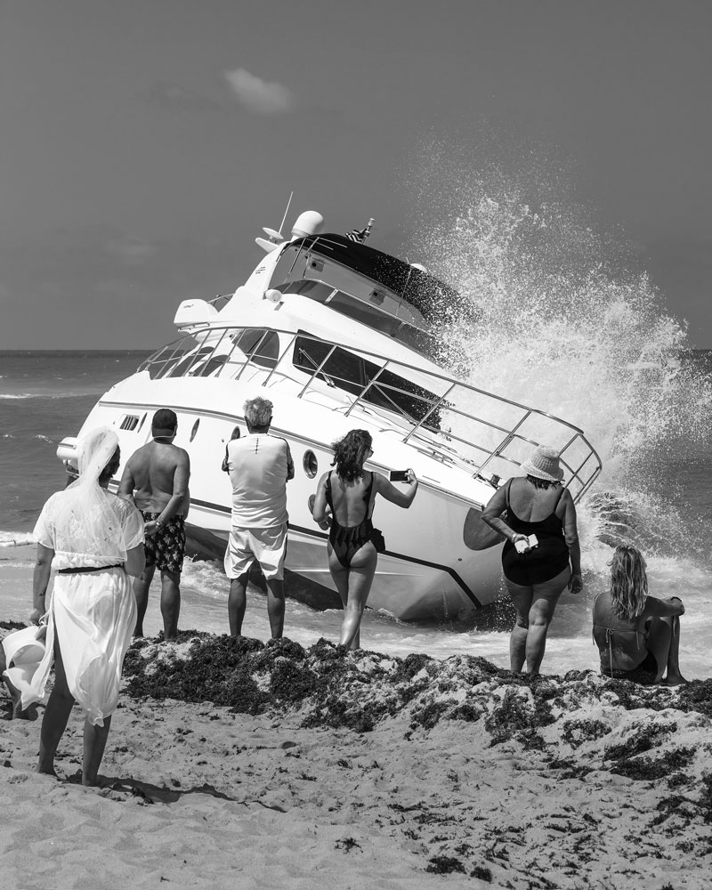 Black and white photograph of beached boat with onlookers