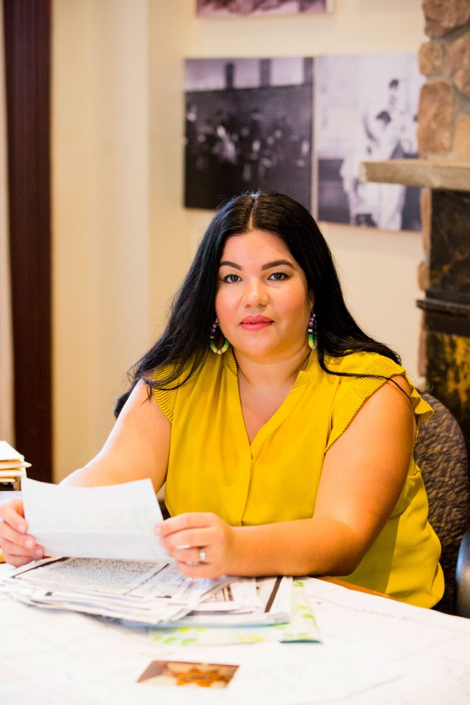 Woman wearing yellow shirt holding a paper. 