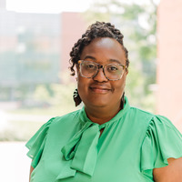 Woman wearing glasses and a green shirt standing outside. 