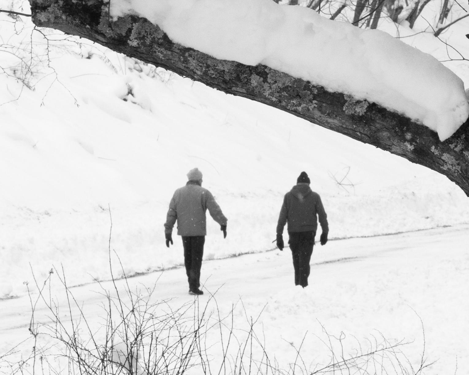 Black and white photograph of two men walking on snowy road